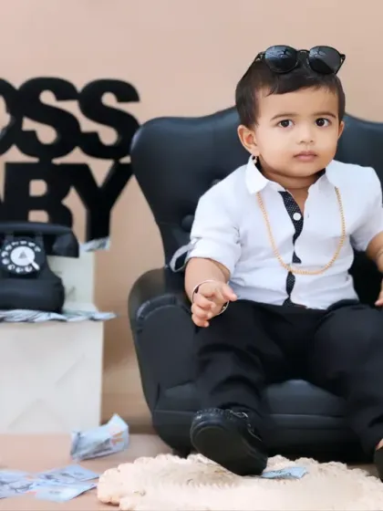 Looking sharp in a white shirt and black pants, this boss baby takes charge from his executive chair.