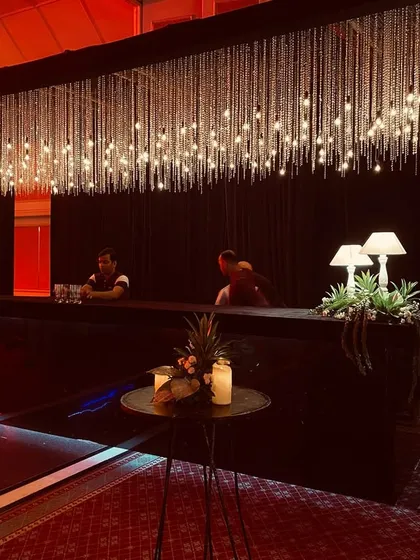 The bar was designed with a curtain of crystal strings and warm lights, creating a sparkling focal point in the dark, moody setting.