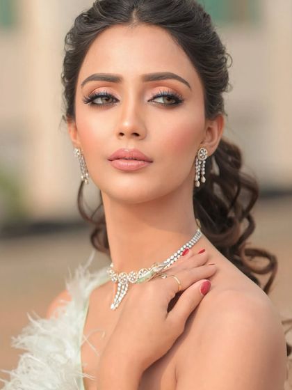 Presenting Valentino. A close-up on a model with shimmery green eyeshadow and a delicate diamond necklace.