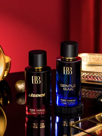 A close-up shot of two perfume bottles styled with luxurious props like a golden tray and a fabric rose. The lighting is carefully controlled to make the glass shine while minimizing harsh reflections, a process that requires extensive cleanup in post-production.