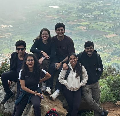 A group of friends posing on the rocky terrain of Skandagiri, with the vast landscape behind them.