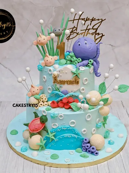 We brought an underwater world to life with this two-tier choco-chip cake. Designed for a first birthday, it features a friendly fondant octopus, colorful fish, and sea turtles amidst edible coral and waves, creating a vibrant ocean adventure.