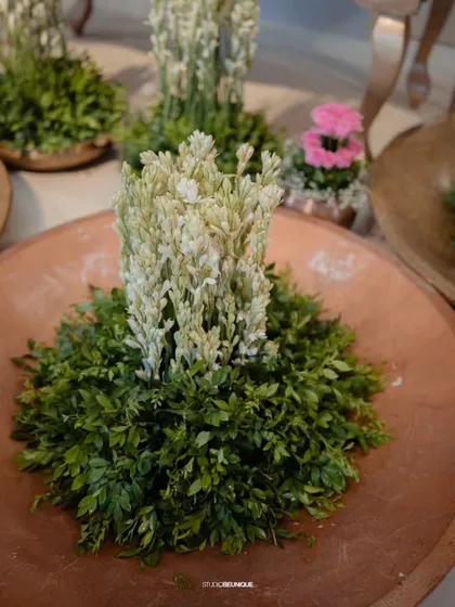 A close-up of a floral arrangement in a terracotta bowl. The contrast of the rustic bowl with the delicate white flowers creates a beautiful, earthy aesthetic.
