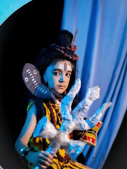 A powerful close-up of our Little Shiva theme. The focus is on the child's expressive eyes, the tripundra on his forehead, and the miniature trishul he is holding.