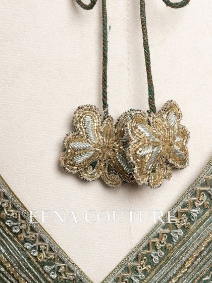 I designed this sage green raw silk blouse with geometric handwork for a timeless yet modern feel. The linear beadwork is complemented by custom floral tassels, making it a versatile piece for any occasion.