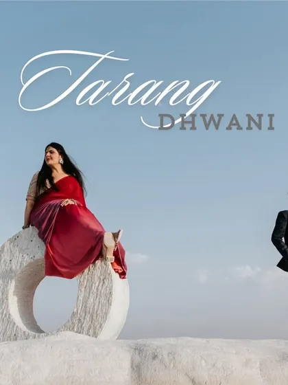 A dramatic and artistic pre-wedding portrait set in Jaipur. The bride, in a flowing red gown, sits atop a modern sculpture against a vast sky, creating a powerful and visually stunning image.