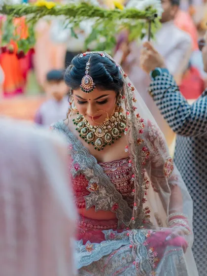 The bride's gentle smile as she walks under the phoolon ki chadar. This is a classic Indian bridal entry shot, filled with tradition and emotion.