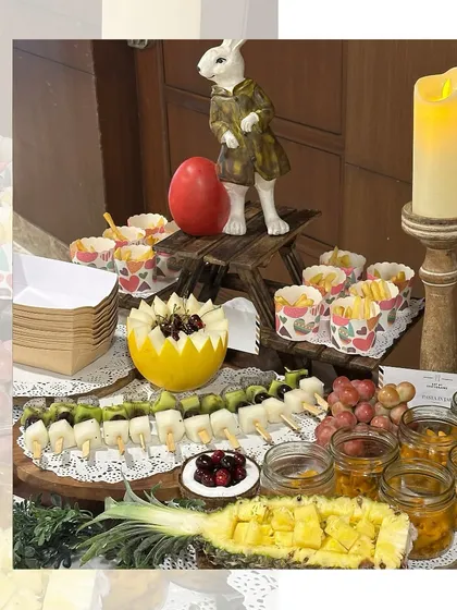 A whimsical grazing table for a kids' party, featuring fruit skewers, mini fries, and other fun bites. The setup is decorated with cute rabbit figurines and candles, adding to the magical theme.