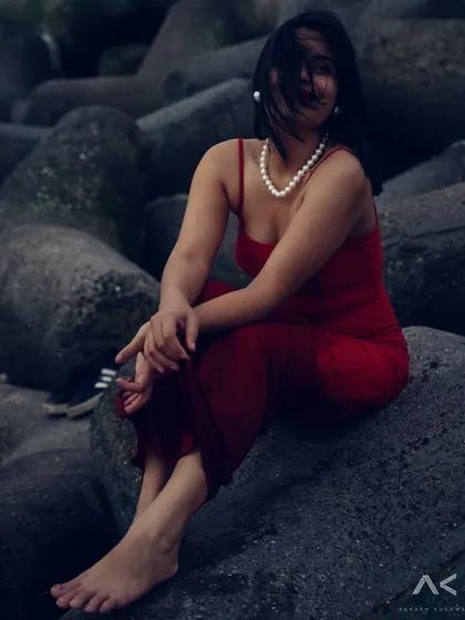 A collection of portraits featuring a model in a red dress on the rocks and by the water. The series explores different poses and moods, from serene to powerful.