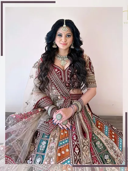 A seated portrait showcasing the full flare and intricate paneling of this colorful bridal lehenga.