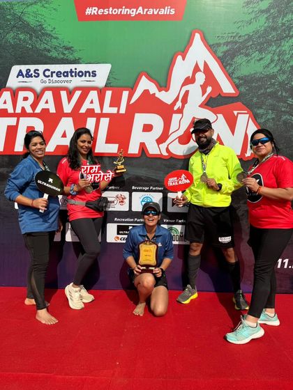 A group of runners posing with their trophies and medals on the podium. The spirit of victory is contagious.