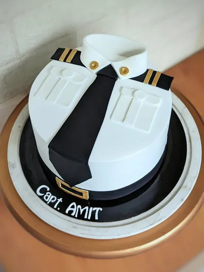 A sharp and elegant cake designed to look like a captain's uniform. This was created for a pilot's celebration, featuring clean fondant work, crisp collar details, and golden epaulets. It's a perfect example of a professional theme cake that is both personal and sophisticated.