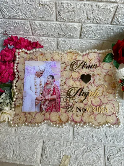 A clear, frontal shot of the frame, highlighting the golden text of the names and wedding date against the backdrop of preserved petals.