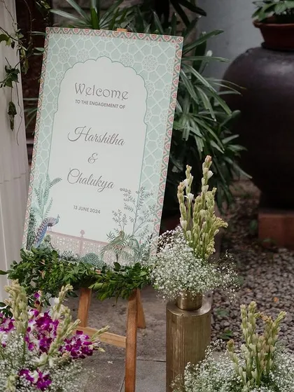 A close-up of the pastel-themed welcome sign, surrounded by purple and white flowers.