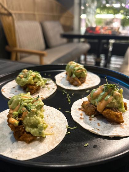 Crispy avocado tacos from 145 Cafe & Bar. The composition of this shot, with the tacos arranged neatly on a dark plate, makes the green of the avocado pop.