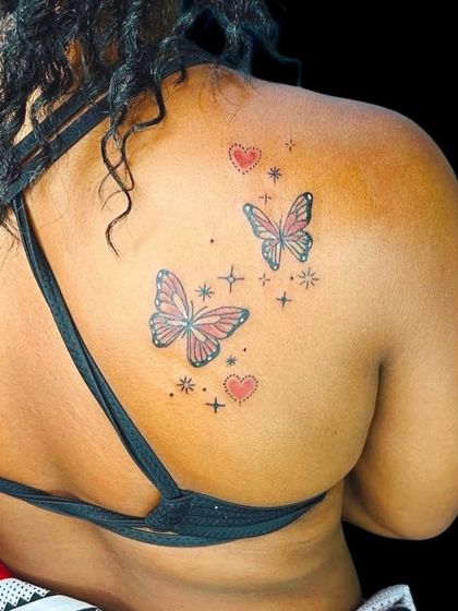Colorful butterfly tattoos with stars and hearts on the back.