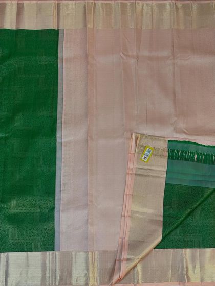 The pallu and blouse piece of a gorgeous tissue silk saree. This one features a half-and-half design with a peach-toned body and a contrasting green pallu, perfect for a subtle yet elegant statement.