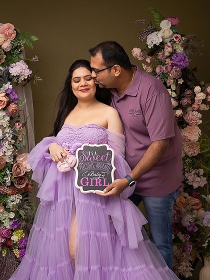 Announcing their sweet baby girl with a cute sign and tiny pink shoes. Using props like these adds a fun and personal touch to your maternity announcement photos.