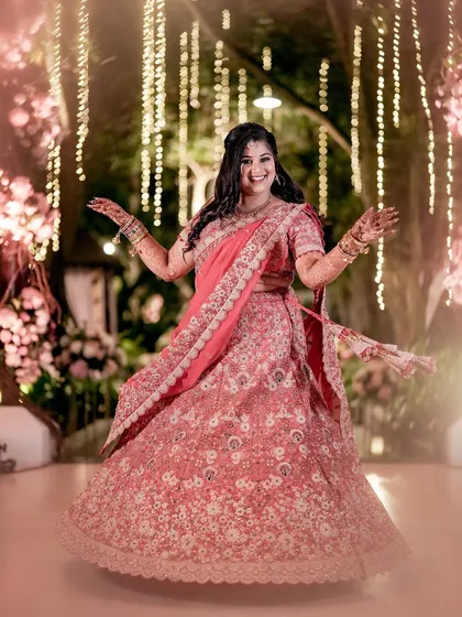 Our beautiful bride Bhumi, twirling in her stunning pink lehenga at her reception. The backdrop of fairy lights and floral decor created a magical setting for her to shine.