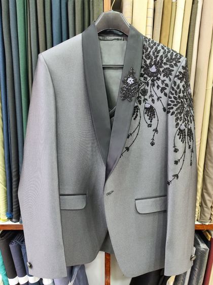 A designer suit jacket in grey with intricate black bead and thread embroidery on the shoulder. This is a custom piece I created for a groom's reception.