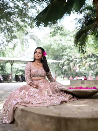 A wide shot of the model sitting on a bench. The natural surroundings and her elegant pose create a beautiful and serene image.