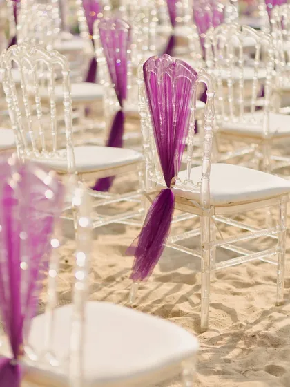 Even the seating was a design element. Ghost chairs on the sand were accented with pleated purple fabric, adding a touch of modern elegance and tying into the lilac color palette of the sunset ceremony.