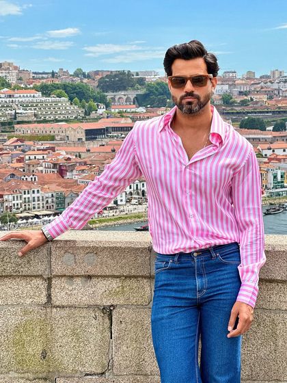 A close-up portrait, the soft pink stripes of the shirt add a touch of warmth and charm to the overall look.