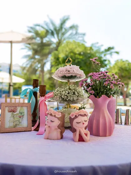 A close-up of a tablescape with adorable face-planter candles and a tiered stand of flowers, highlighting the cute and whimsical details of the event.