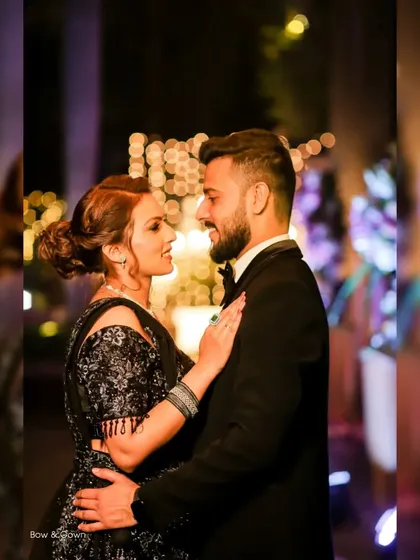 A lovely reception portrait where the couple is looking at each other with bright smiles. The background lights create a magical, festive feel.
