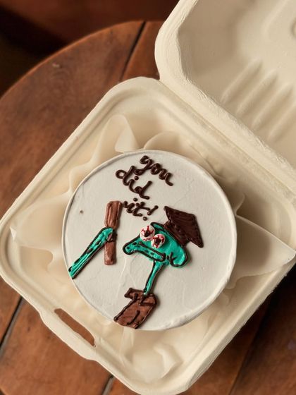 A fun graduation or achievement cake featuring Squidward from Spongebob Squarepants, with the message "you did it!". It's a quirky way to say congratulations.