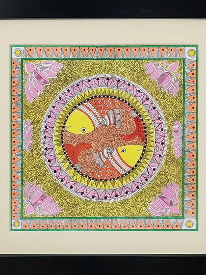 Two fish swim in a circle in this Madhubani painting by Neha Kumari. The piece is rich with color and texture, from the golden-green background to the pink lotus flowers in the corners.