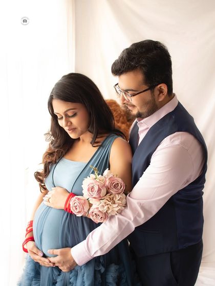 A sweet couple's portrait. His hand gently rests on her baby bump as they share a quiet moment in our Noida studio.