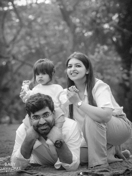 A playful family pose in the park, with the little girl sitting on her dad's back. A timeless black and white memory.