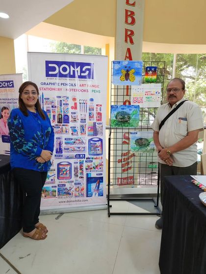 Posing with a fellow organizer beside the display of children's art. These community collaborations are essential for making art accessible to all.