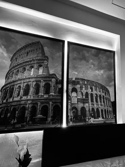 The large, black-and-white prints of the Colosseum above the bed are backlit, adding a dramatic and sophisticated touch to the room.