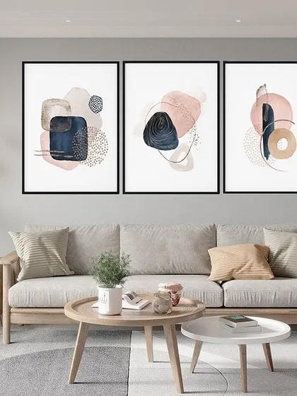This triptych of framed prints features abstract compositions in shades of navy, pink, and beige. The mix of textures and shapes creates a sophisticated and modern gallery wall that is both calming and visually interesting.