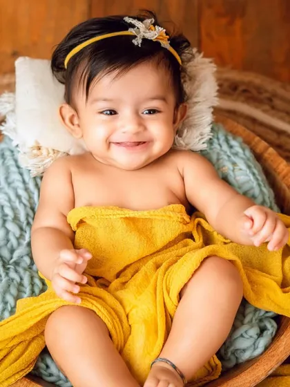 Sitter sessions are perfect for capturing those adorable smiles before they start crawling. This simple, cozy setup with a warm yellow wrap highlights this baby's happy personality.