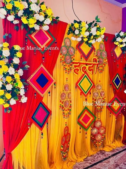Another angle of the colorful Haldi/Mehendi backdrop, showing the asymmetrical arrangement of flowers.
