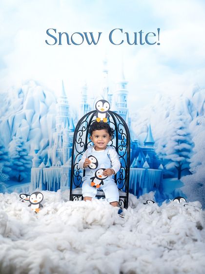 Snow Cute! This little prince sits on his icy throne, ready to rule his winter wonderland. The penguin props add a touch of playful charm.