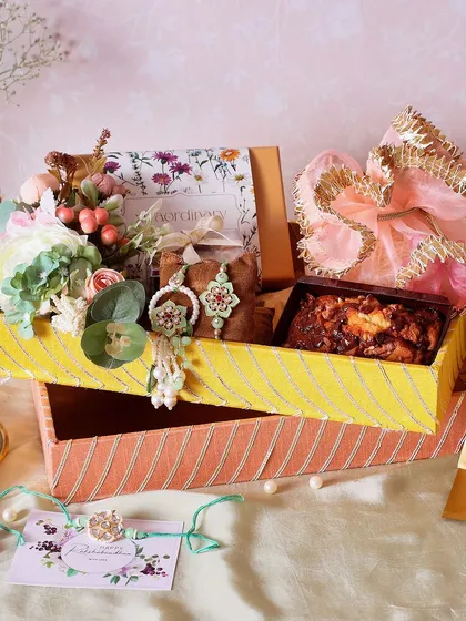 The Traditional Gota Tray Rakhi Hamper is perfect for a classic celebration. It includes a fudge brownie box, a walnut & chocolate tea cake, and NYC chunk cookies.