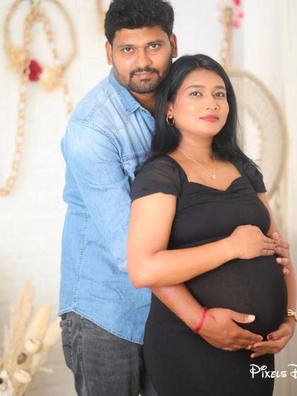 A sweet and simple couple's portrait in a bohemian setting, with the mom-to-be in a classic black fitted dress.