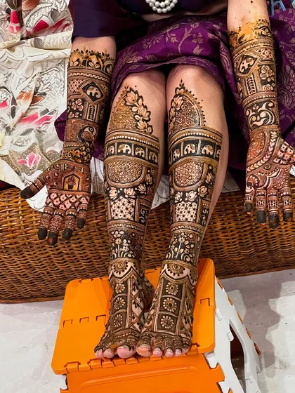A complete bridal look with mehendi on both hands and feet. The designs are coordinated, featuring elephants, lotuses, and intricate geometric patterns for a stunning effect.