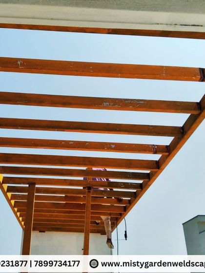 A low-angle view of the pergola framework against the sky. This perspective emphasizes the strength and scale of the structure being built.