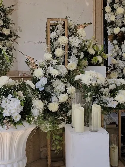 A lavish display of white flowers in various arrangements, using wooden frames and classic white urns to create a stunning photo corner.