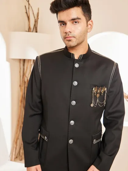 A closer look at the upper portion of our black bandhgala. This view highlights the contrast piping along the shoulder and pocket, along with the custom metallic brooch that adds a touch of individuality.