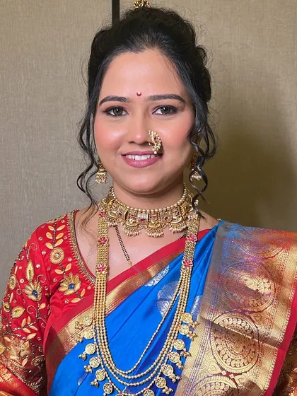 A wedding-ready bride in a blue and red saree. The makeup is flawless, with traditional jewelry completing the classic Maharashtrian look.