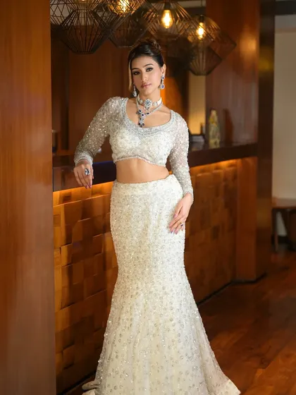 Striking a pose. The lighting catches the shimmer in her makeup and the sparkle of her outfit, showcasing a look that is pure glamour.