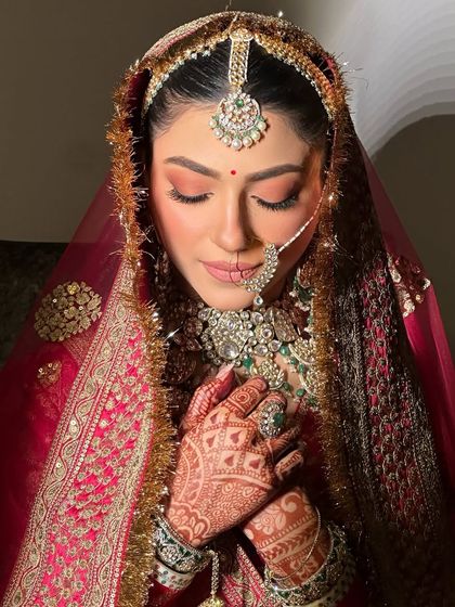 A serene moment captured. The soft, warm tones on her eyes complement the rich colors of her lehenga perfectly.