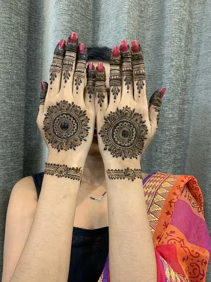 A fun pose showing off matching mandala designs. This is a popular choice for friends getting their henna done together for a festival.