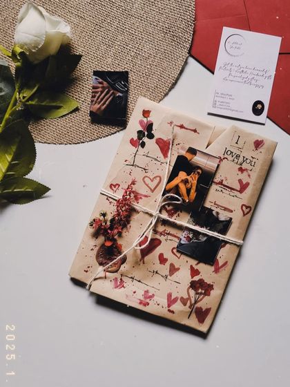 A Valentine's gift wrapped in custom-painted paper, tied with twine and adorned with a mini bouquet.